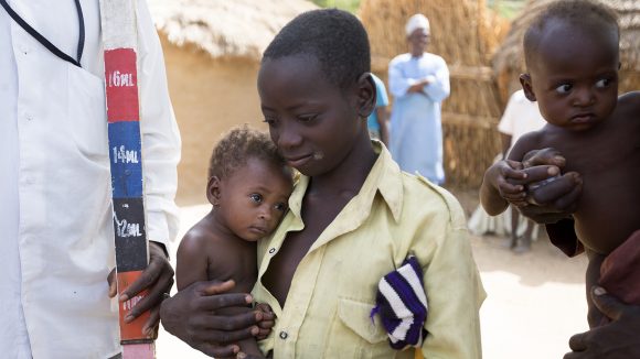 A boy and his baby brother wait to be given medication to treat NTDs in Nigeria.