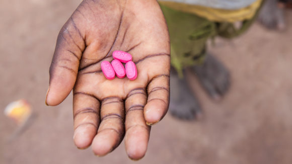 A child in Senegal holds Zithromax tablets in his hand.