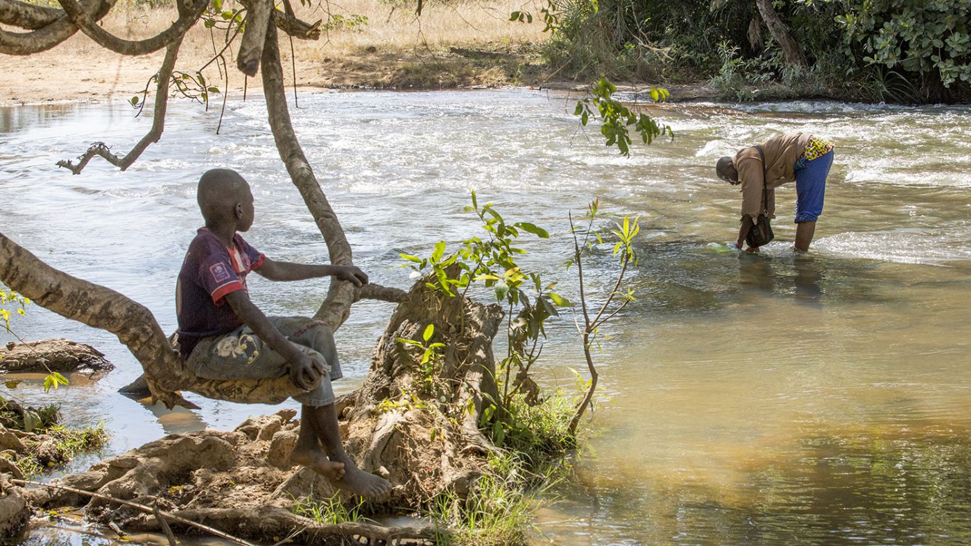 A man sits by a river.