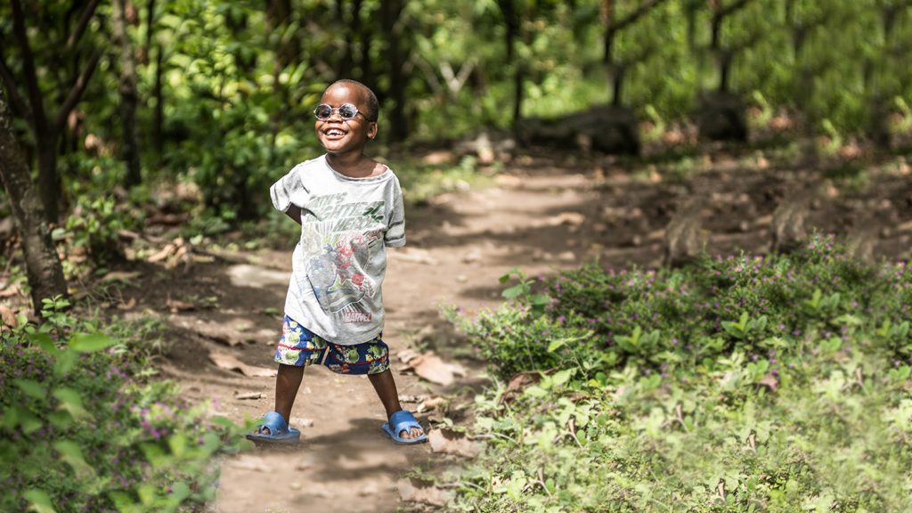 A small boy smiles while wearing his new glasses.