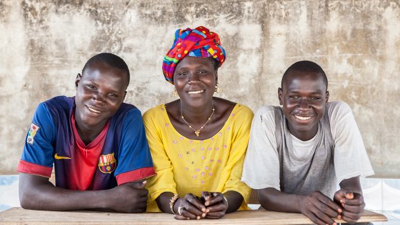 Tre persone sono sedute ad una scrivania e sorridono