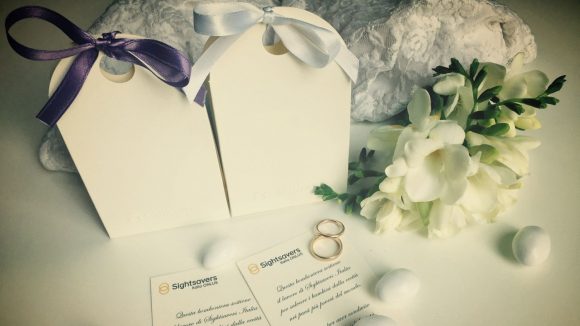 Su un tavolo sono presenti due scatoline due bigliettini due fedi e dei fiori.