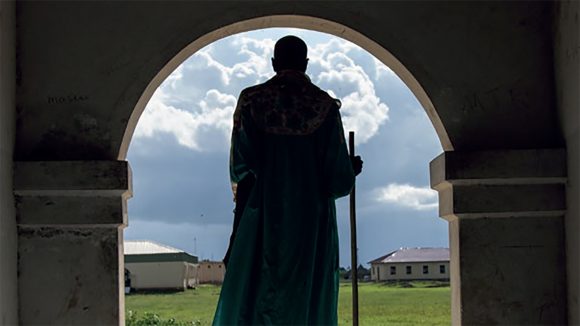 La sagoma di un uomo in piedi davanti ad una parta con dei campi sullo sfondo.