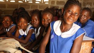 A scuola una ragazzina in primo piano sorride e dietro di lei altre ragazzine sorridono.