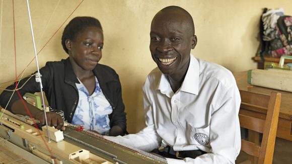 Un uomo cieco sra lavorando a maglia con l'aiuto di un insegnante.