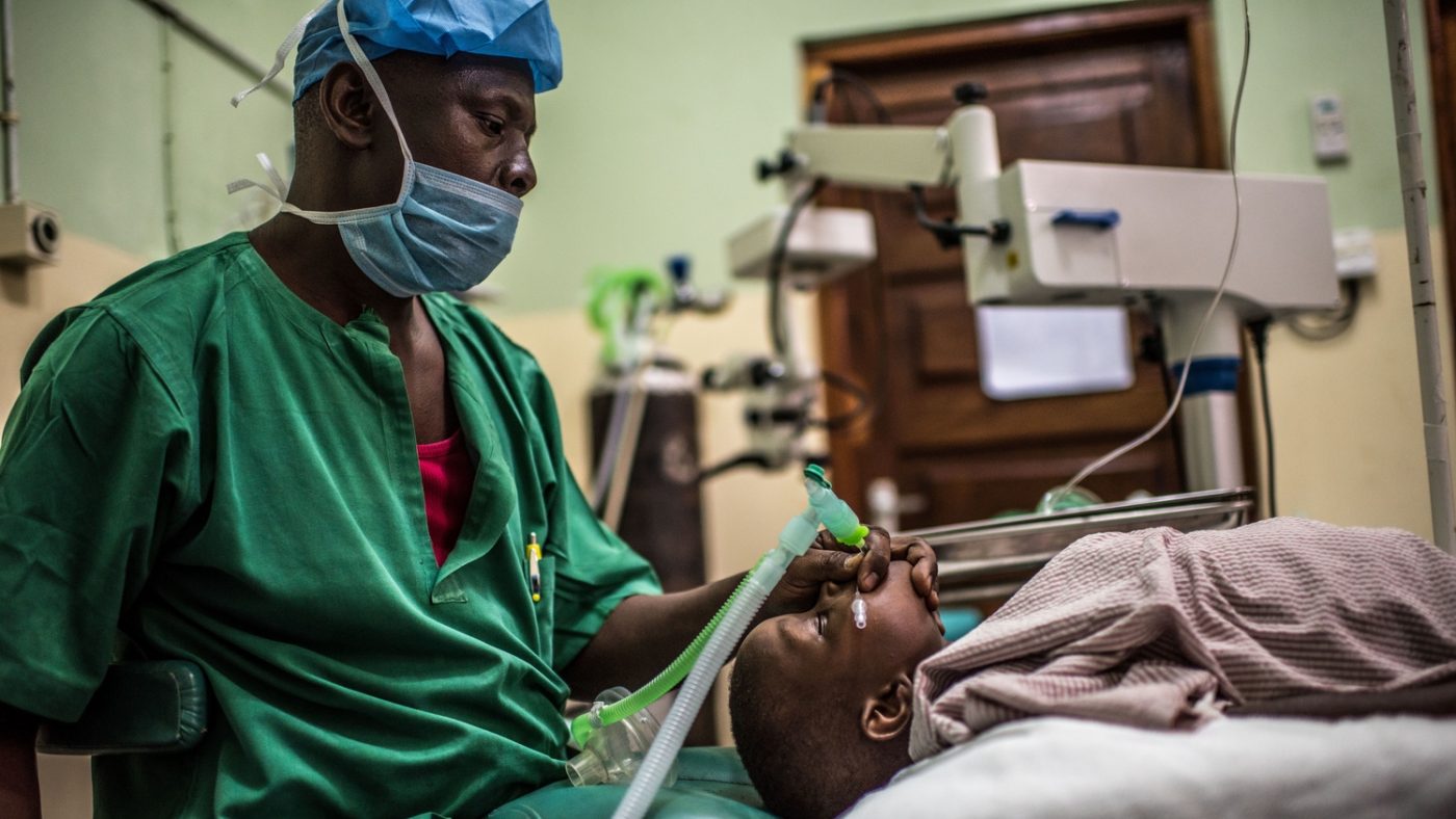 In sala operatoria un dottore con la mascherina inserisce un tubo per la respirazione nella bocca di un bambino sdraiato su un lettino.