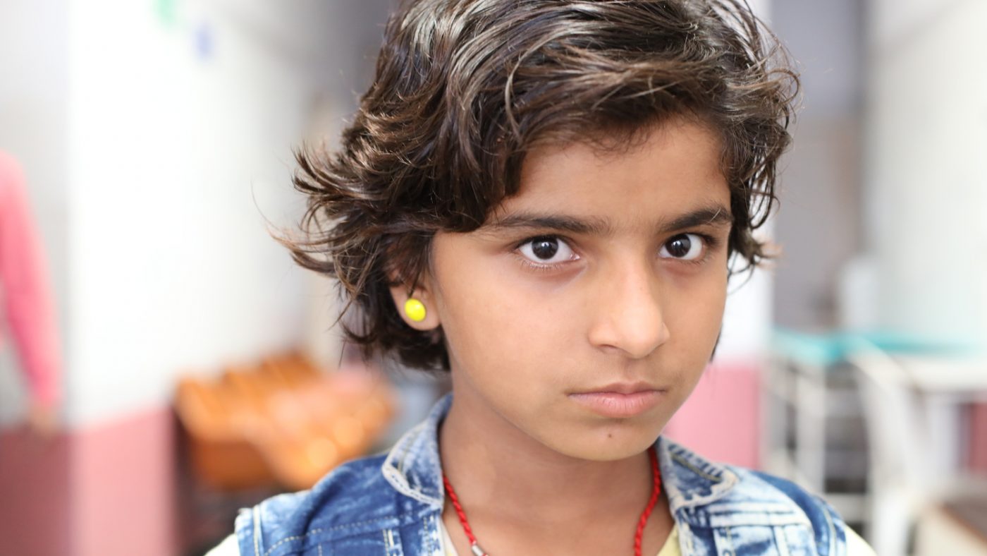 Una bambina con gli orecchini gialli guarda davanti a sè.