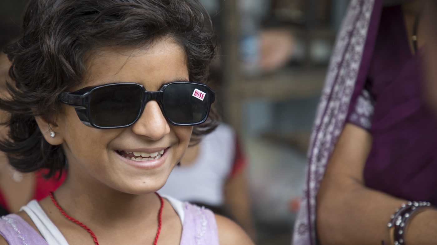 Una bimba indossa gli occhiale da sole e sorride.