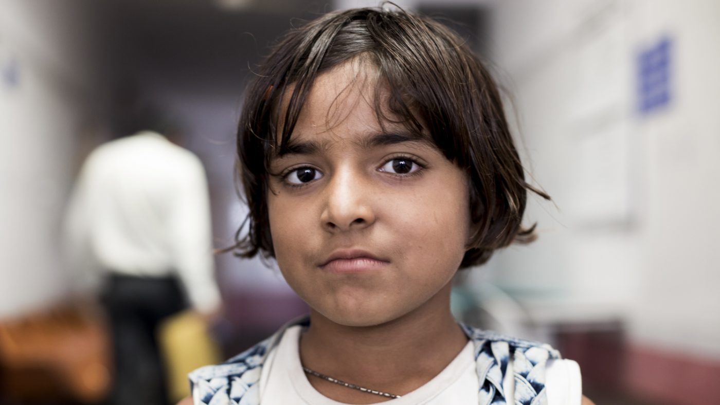 Una bambina guarda davanti a sè con un espressione seria.