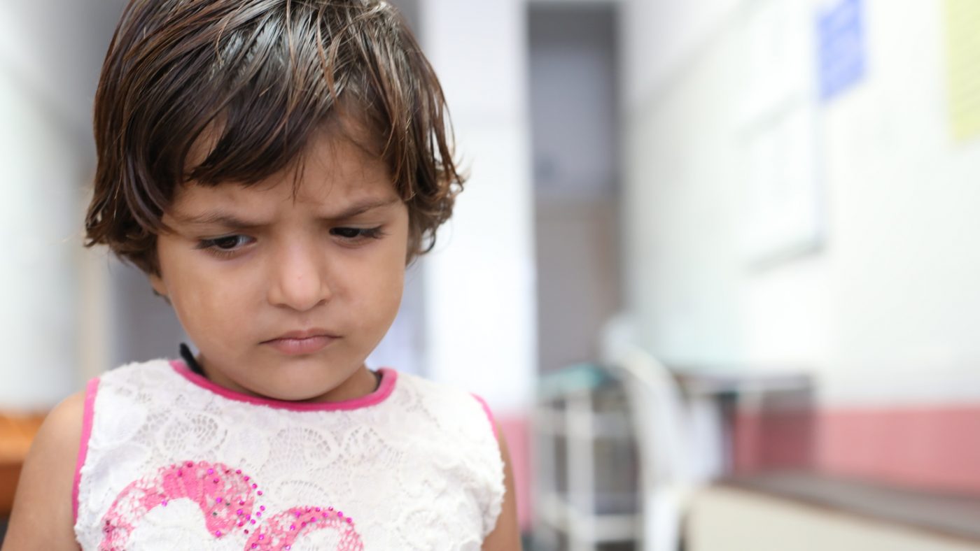 Una bambina in primo piano ha lo sguardo corrucciato.