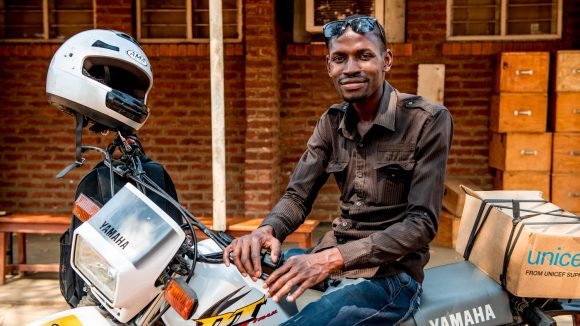 Madalitso sorride in sella alla sua motocicletta.
