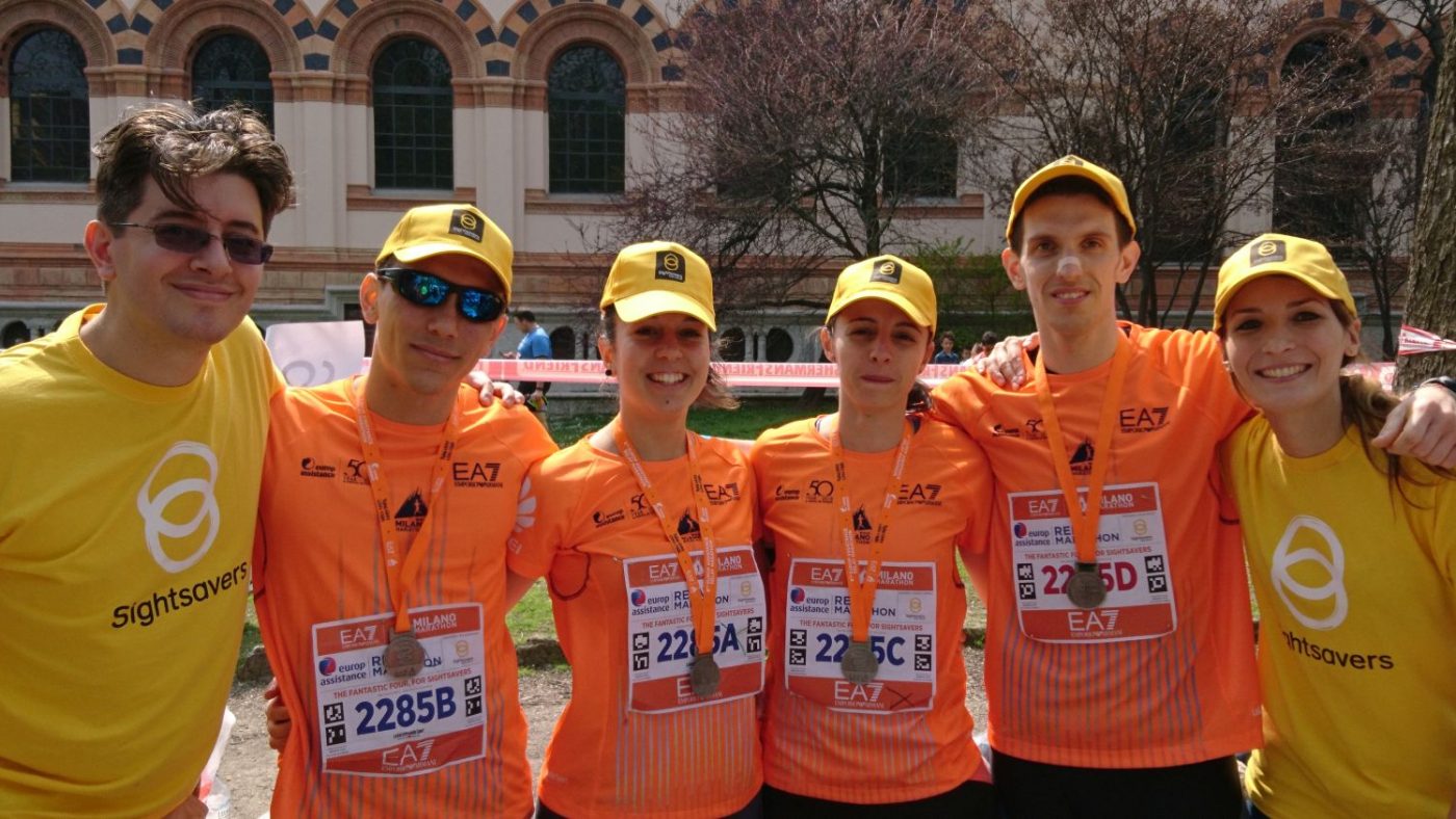Tre uomini e tre donne stanno guardando davanti a loro indossano la pettorina della maratona e la maglietta di Sightsavers