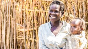 Una donna sorride tenendo in braccio il suo bambino.