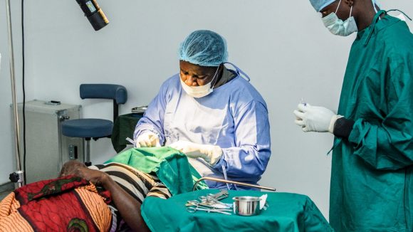 Un dottore opera una paziente sul lettino della sala operatoria.
