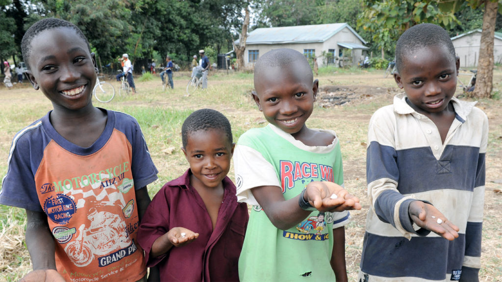 Children in Cameroon hold tablets that they will take to prevent the spread of diseases such as trachoma.