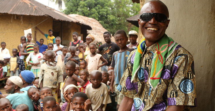 A man and a large group of children smiling and looking at the camera.