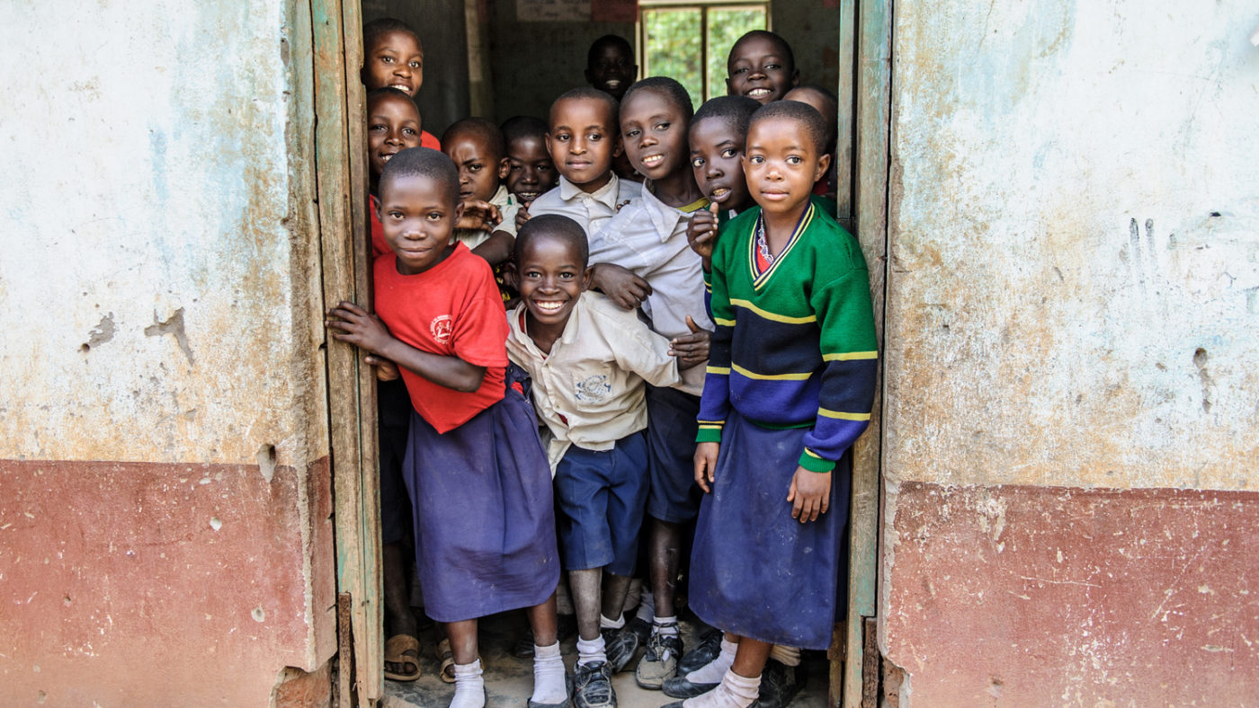 Un gruppo di bambini sulla porta sorride all'obiettivo.
