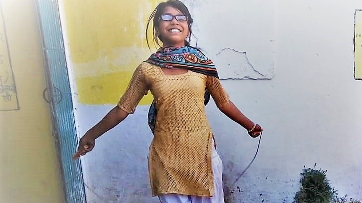 Una ragazzina con gli occhiali salta la corda.