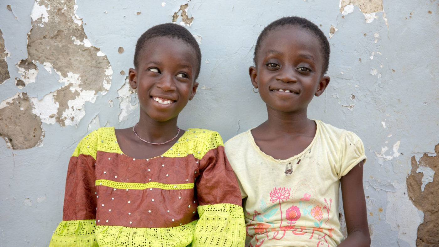 Two young girls sitting together and smiling.