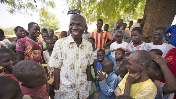 Sightsavers surgeon Aliyu smiles with a group of children.