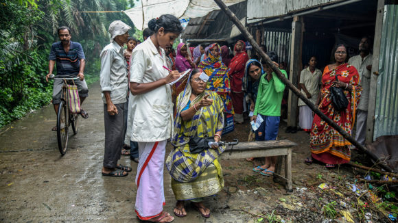 A woman has her eyes checked by an eye health worker in an outdoor screening camp in India.