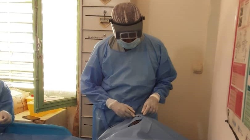 Babacar performs surgery wearing protective equipment on a trachoma patient.