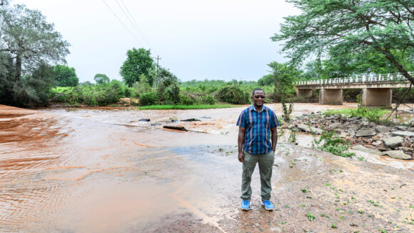Senior programmes lead in Zimbabwe, Peter Bare, stands next to a flooded road.