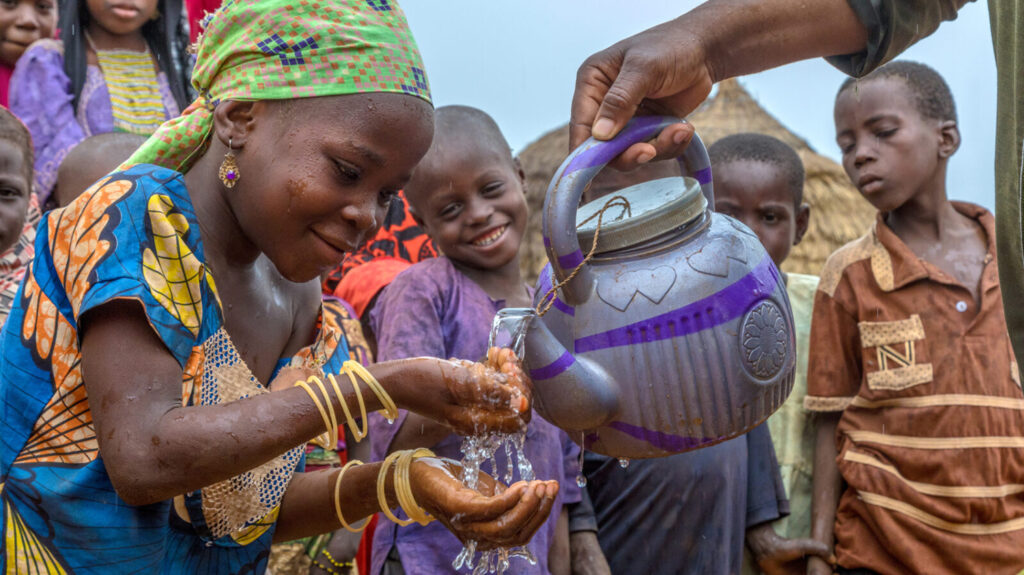A girl in Nigeria learns how to use water to wash her face and hands.
