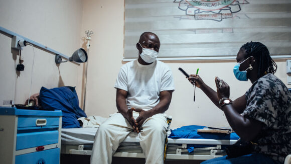 A patient is interviewed by a member of Sightsavers staff as part of a project.