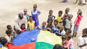 Children play with a parachute outside.