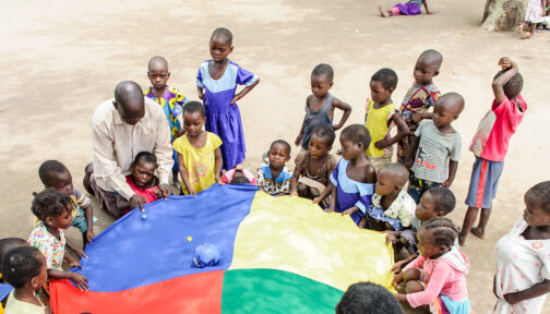 Children play with a parachute outside.