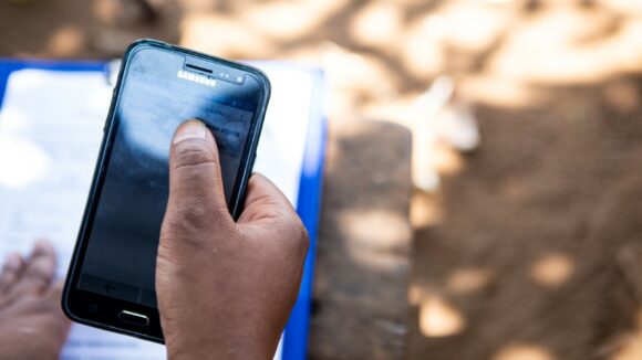 A person's hands are shown, entering data into a mobile phone.