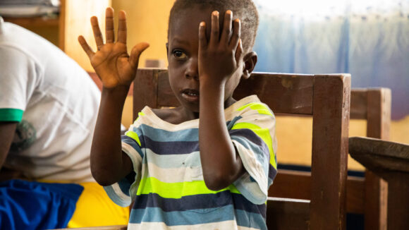 Un bambino si copre un occhio con la mano.