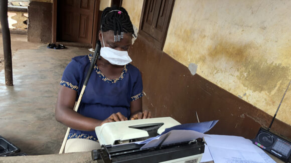 A girl uses a typewriter while wearing a face mask.