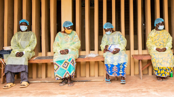 Four patients wait while socially distancing for their trauchoma surgery while wearing PPE and face masks.
