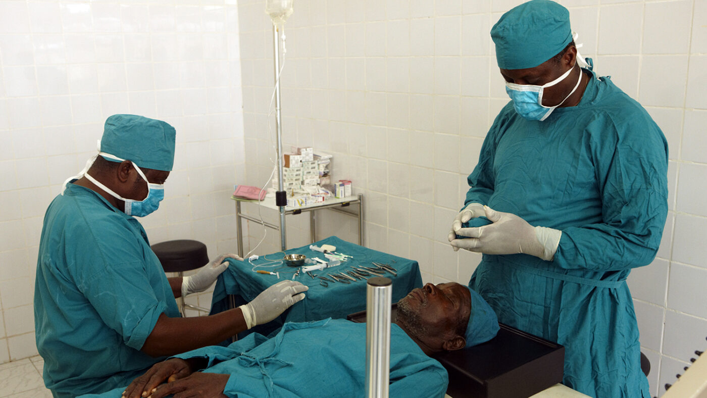 Two surgeons dressed in scrubs prepare to carry out a cataract operation on a patient.