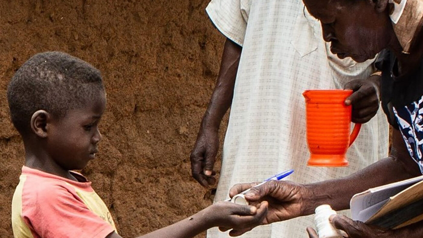 Un bambino prende una medicina da una volontaria.