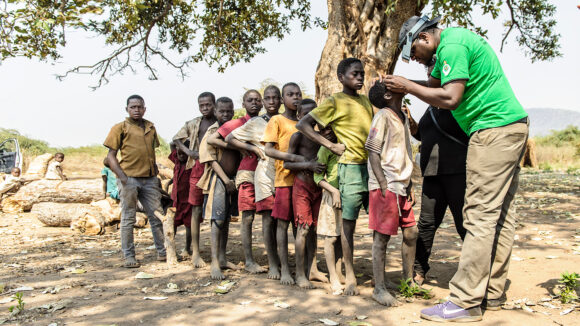 Children in Malawi queue up to have their eyes checked by an eye health worker.