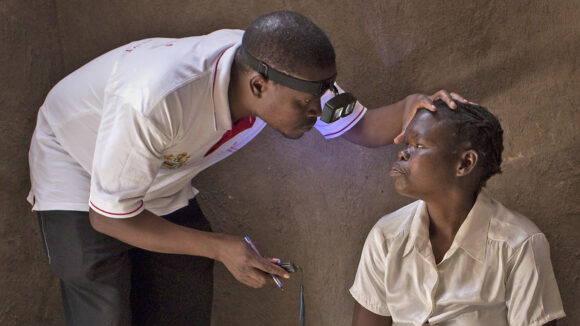 An eye health worker in Malawi checks a woman's eyes for signs of trachoma.