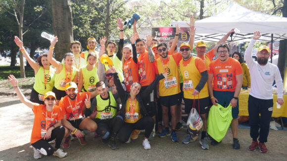 Una ventina di runner stanno salutando davanti allo stand di Sightsavers durante la maratona