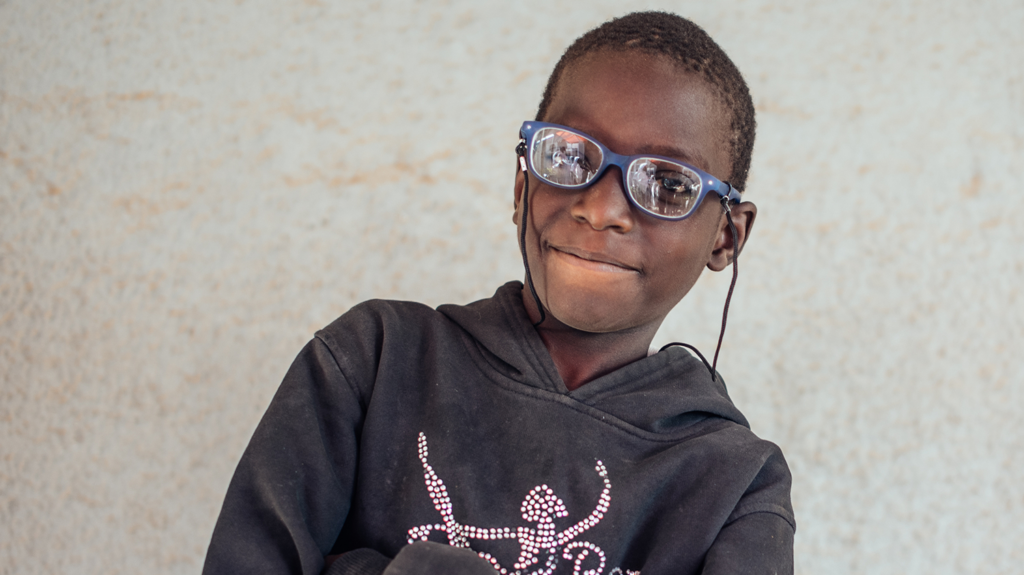 A boy wearing glasses smiling.