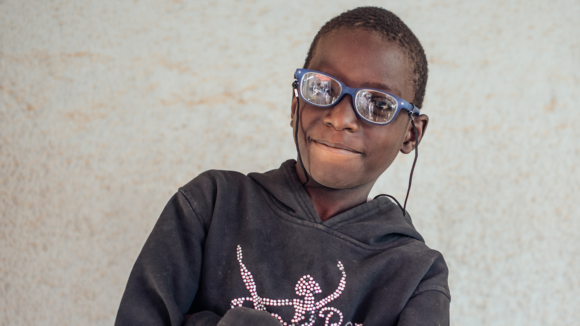 A boy wearing glasses smiling.