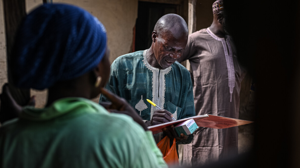 John Hosea, volontario Sightsavers, fornisce i farmaci in un villaggio.
