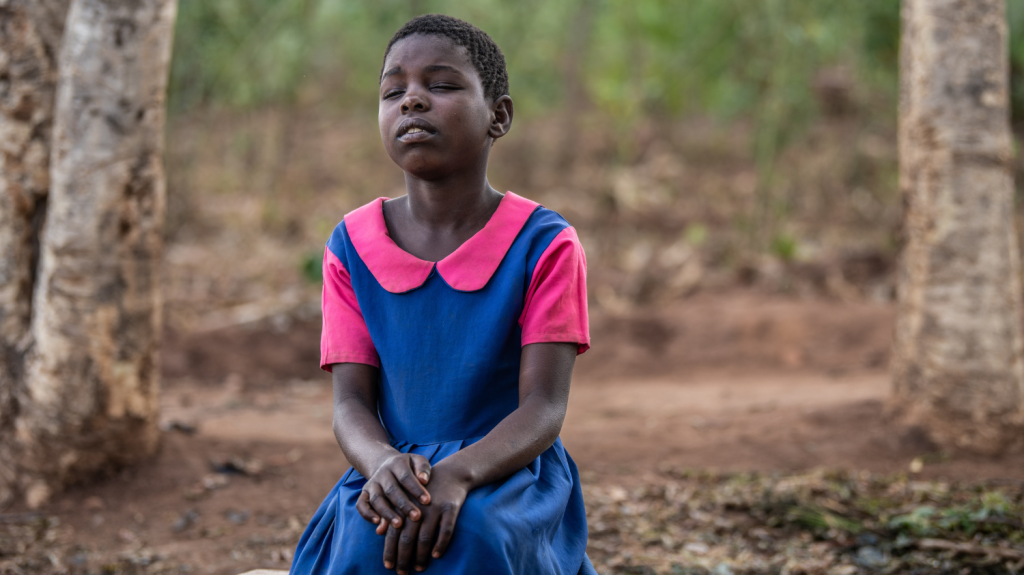 La piccola Melia seduta con gli occhi chiusi e le braccia conserte.