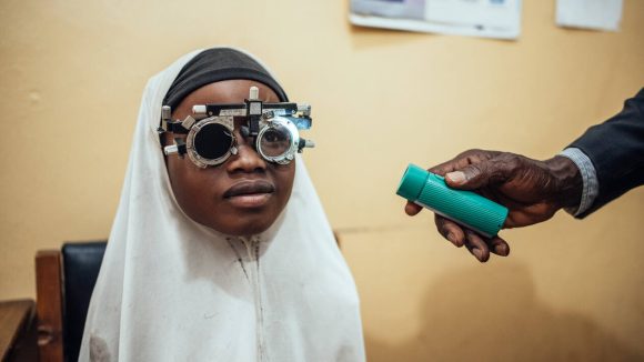 Una bambina indossa una montatura di prova durante una visita oculistica.