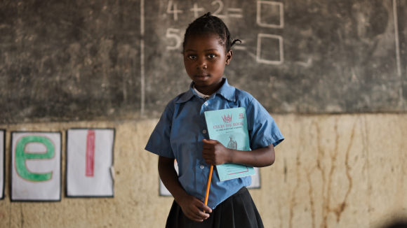 Shileila a scuola con un quaderno e una matita in mano.